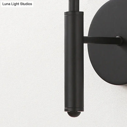 Modern black wall sconce with clear textured glass features a black matte cylindrical stem and circular backplate for bedroom lighting