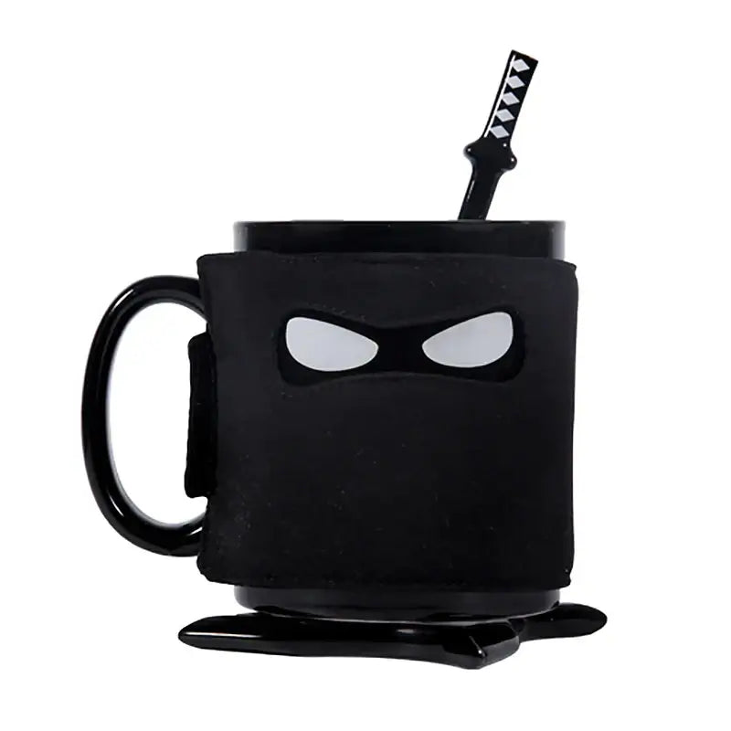 A decorbites black ninja mug with matte finish and white eye cutouts featuring a matching black sword stirrer