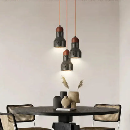 Three decorbites black travertine led pendant lamps with matte black metal and reddish-brown ceramic tops hang on orange cords