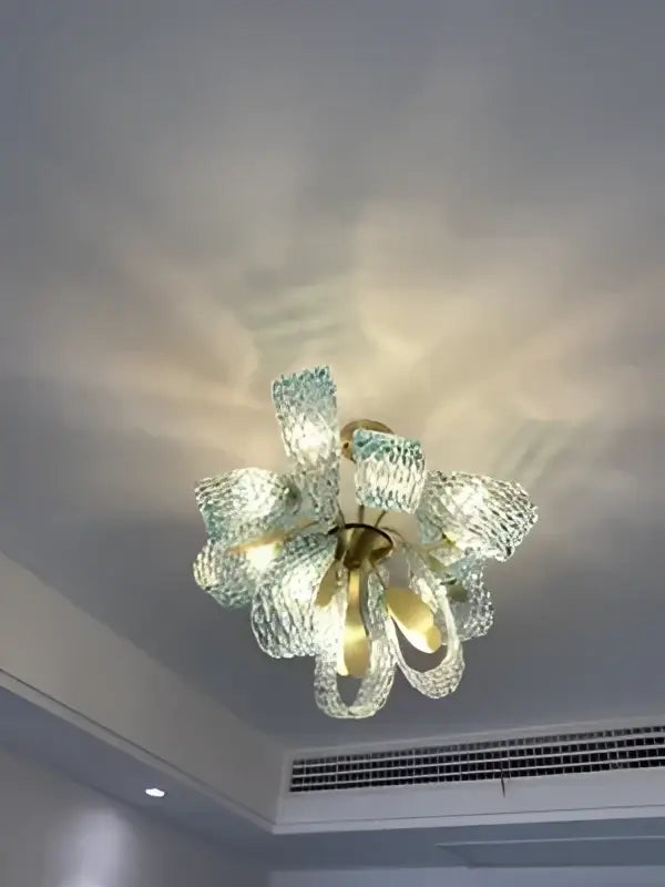 A delicate green glass chandelier with floral design and gold accents in contrast to decorbites blue glass led pendant lamps