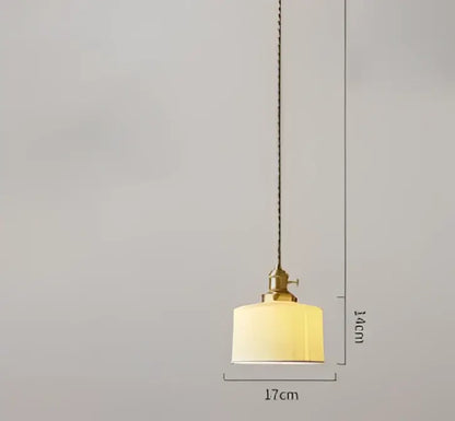 A warm pendant light with a textured off-white fabric shade and brass hardware complementing decorbites blue glass pendant lights