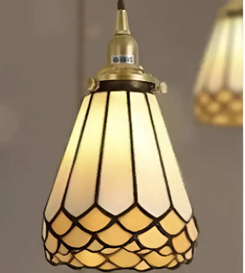 A warm amber-tinted stained glass pendant light with brass scalloped petals, ideal for decorbites blue glass pendant lighting designs