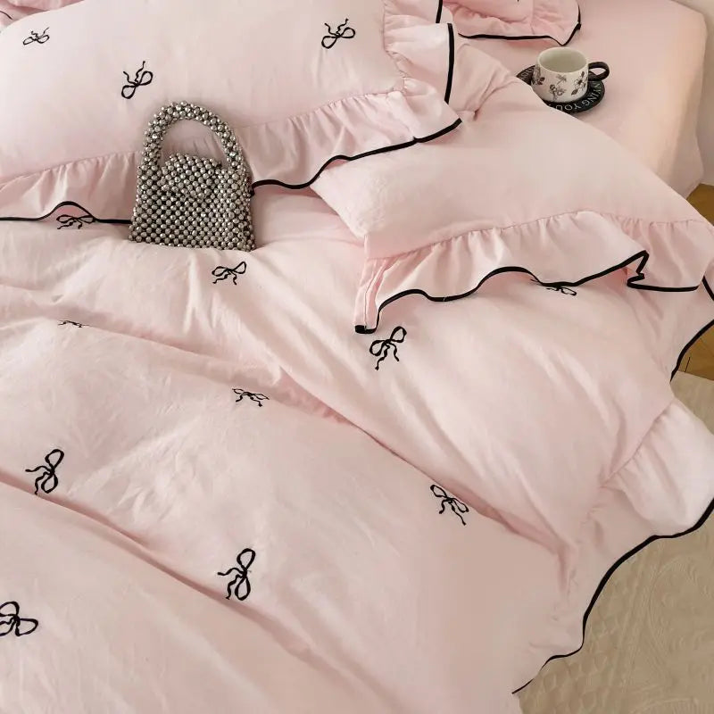 Delicate pink DecorBites™ bow embroidery bedding set with black embroidered bows and ruffled edges