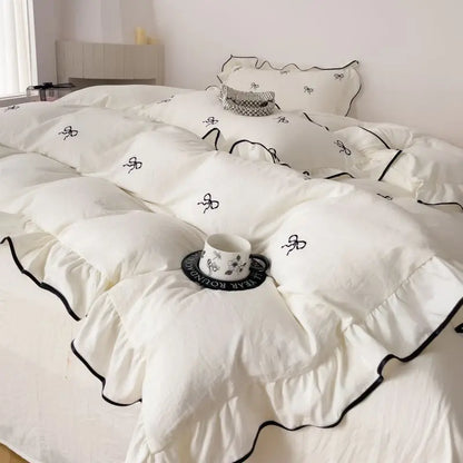 White DecorBites™ bow embroidery bedding set with ruffles featuring black embroidered bow details and matching trim