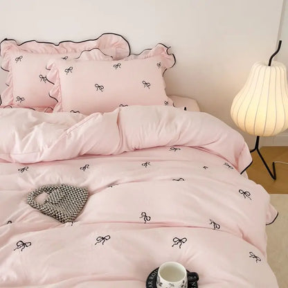 Pink satin DecorBites™ bow embroidery bedding set with ruffles features elegant black bow embroidery and ruffled edges