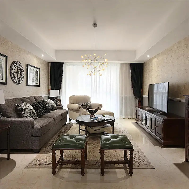 A pair of green tufted leather ottomans with dark wood legs complementing the rose gold black branch design chandelier