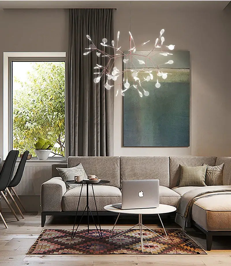 Silver laptop with minimalist design and apple logo on white table next to decorbites branch design nordic chandelier rose gold black