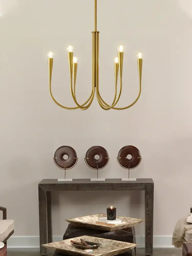Gold-toned decorbites brass chandelier with six curved arms and frosted bulb fixtures for dining room use