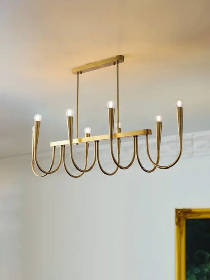 A modern decorbites brass chandelier with sleek curved arms and exposed bulbs for dining room use