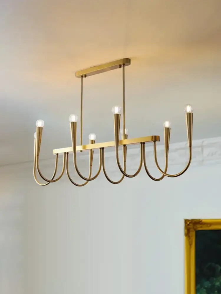 A modern decorbites brass chandelier with sleek curved arms and exposed bulbs for dining room use