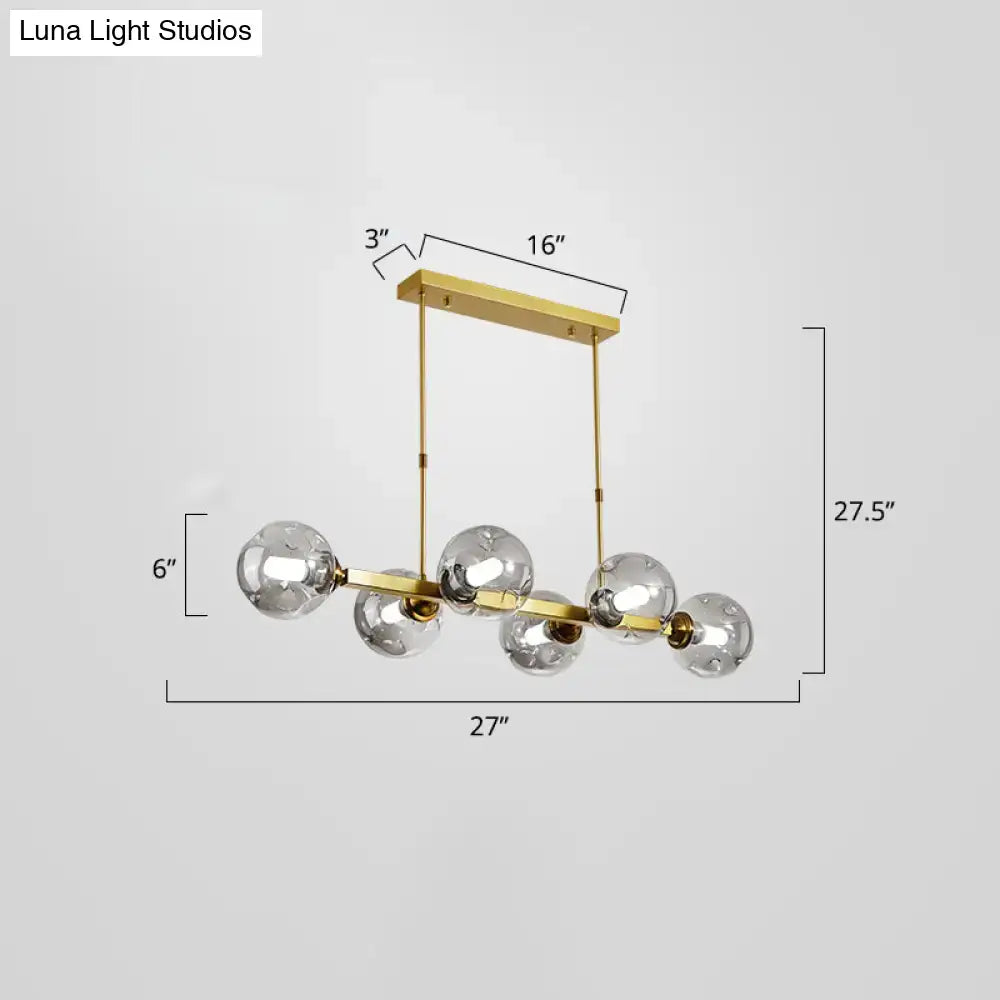 Gold-toned brass DecorBites pendant light features five clear glass globe bulbs in a modern dining island fixture