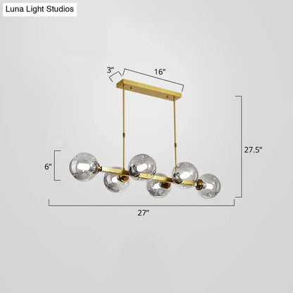 Gold-toned brass DecorBites pendant light features five clear glass globe bulbs in a modern dining island fixture