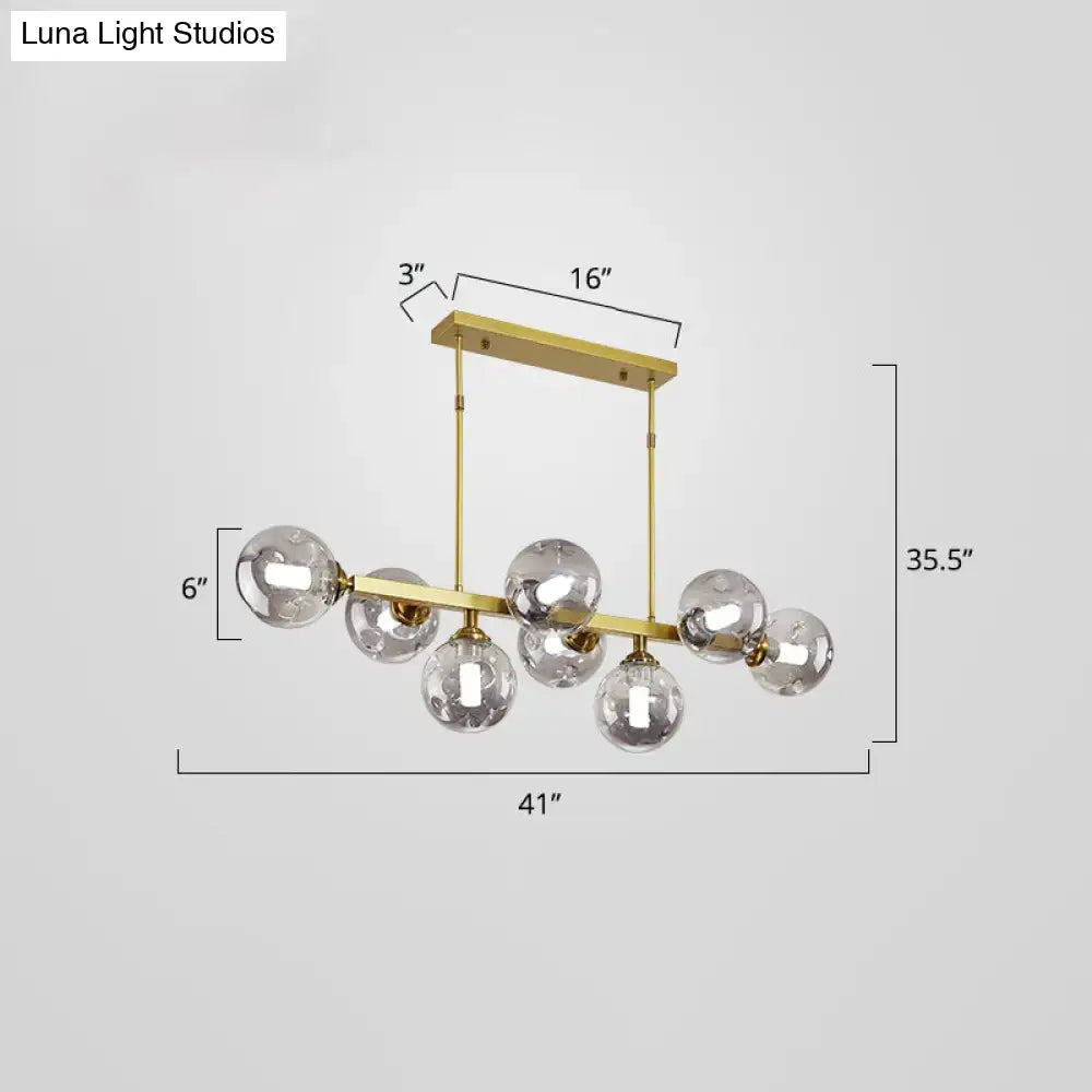 Gold-toned modern pendant light with seven clear glass globe bulbs features stylish light features for dining islands