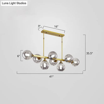 Gold-toned modern pendant light with seven clear glass globe bulbs features stylish light features for dining islands