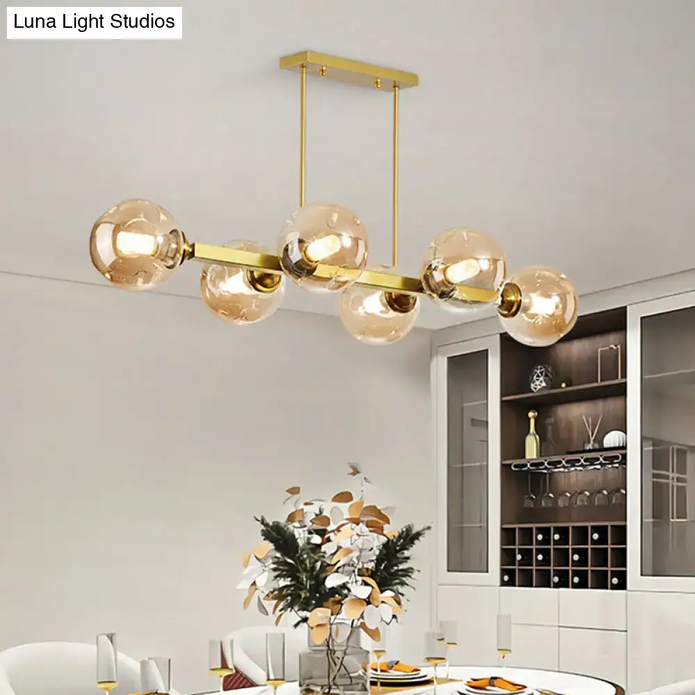 Gold-toned decorbites pendant light with five amber glass globes and sleek metallic frame features stylish island lighting