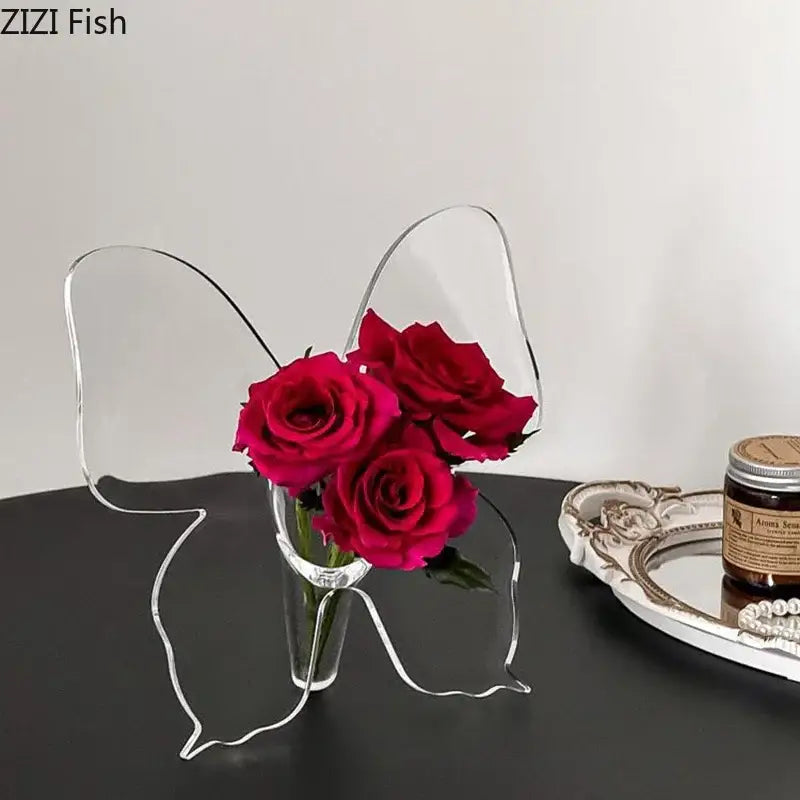Clear acrylic butterfly vase holding vibrant red roses ideal for aesthetic room decor by DecorBites™