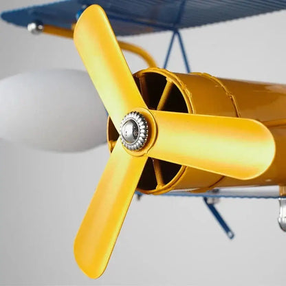Yellow metal propeller with silver hub attached to a blue and yellow decorbites cartoon aircraft fan light for bedroom use