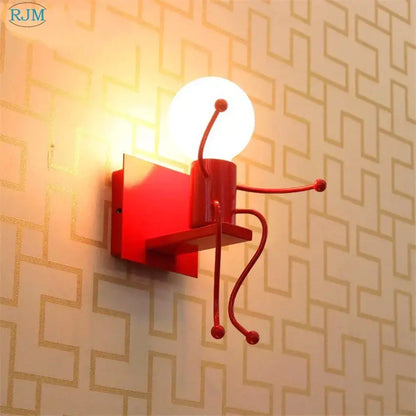 Red metallic cartoon children iron wall lamp by decorbites featuring a seated figure with articulated limbs and glowing head
