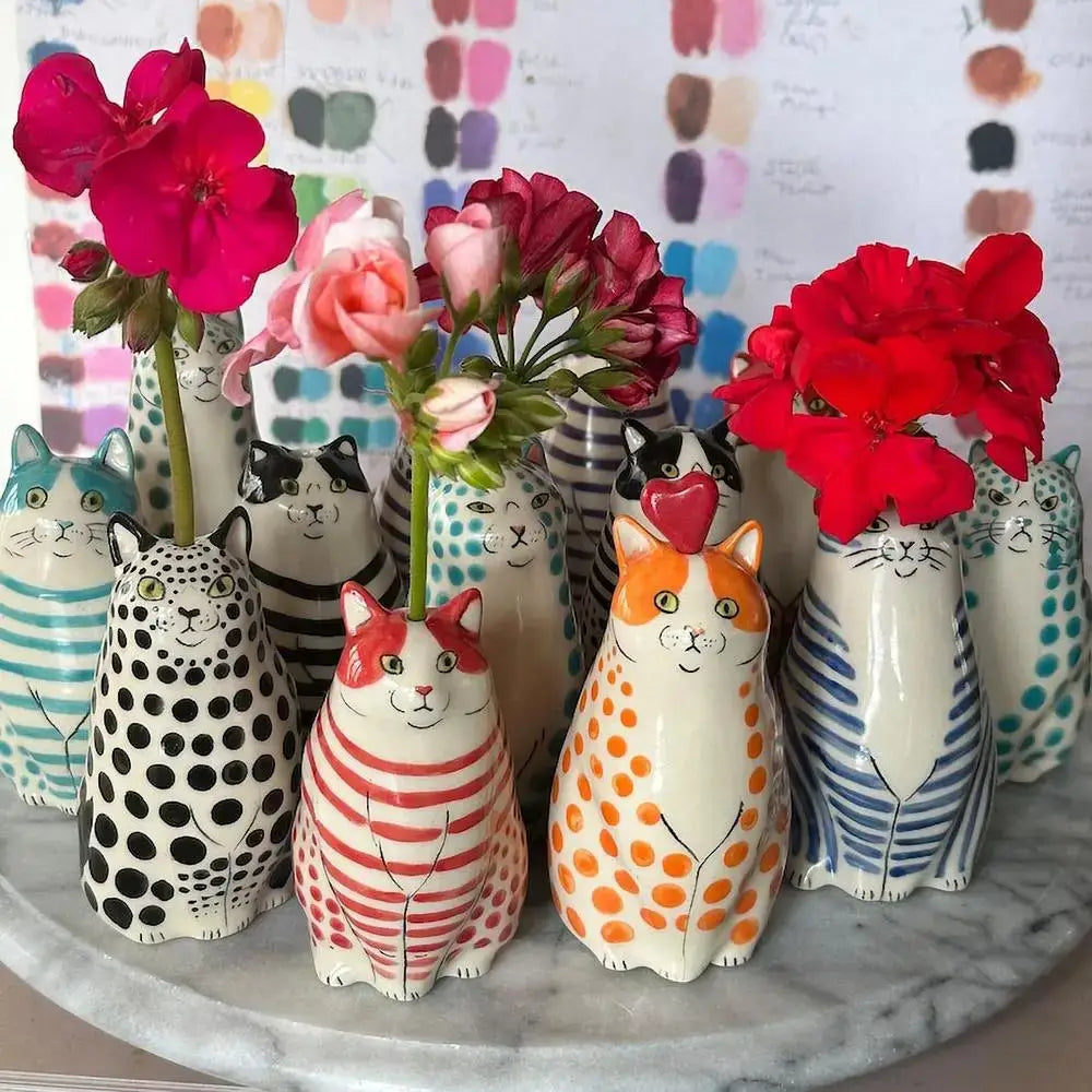 A collection of decorbites™ cat polka dot resin flower bud vases with colorful patterns and painted facial features