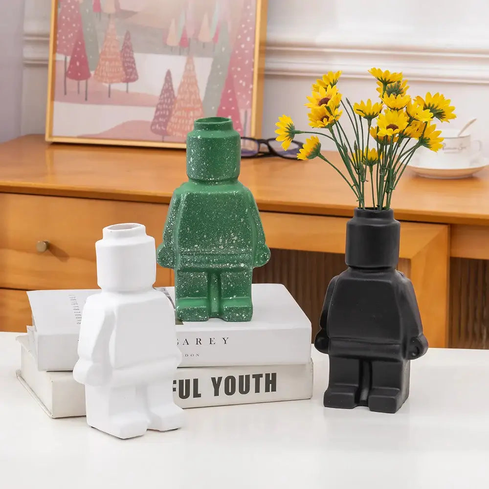 Green glittery ceramic robot vase holding yellow flowers for nordic style home decor by DecorBites