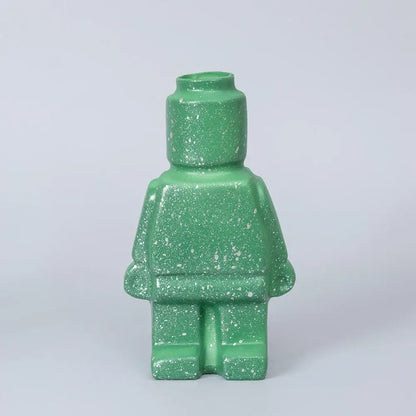 A green speckled ceramic robot vase shaped like a lego minifigure in nordic style home decor by decorbites