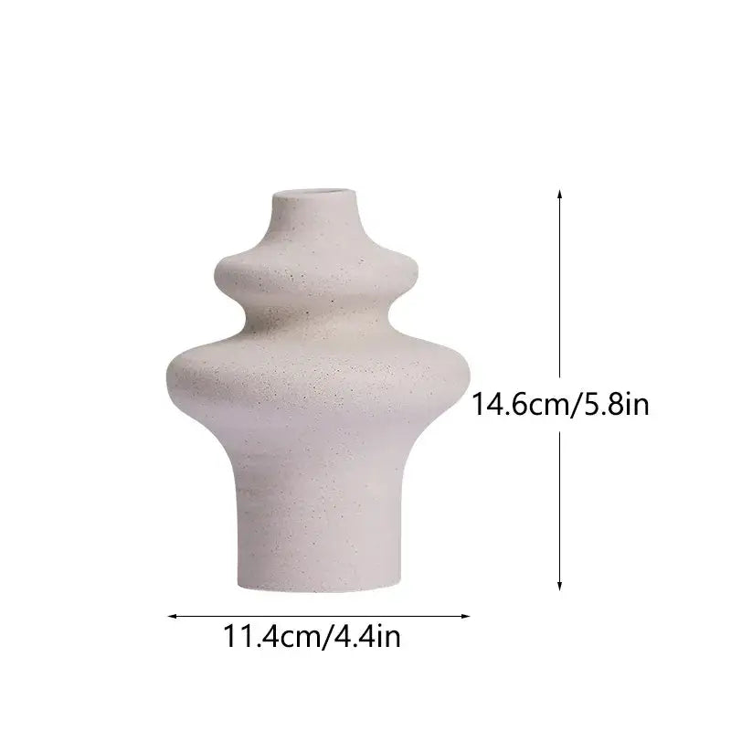 A minimalist off-white ceramic vase with a textured speckled surface and abstract tiered silhouette for modern home decor