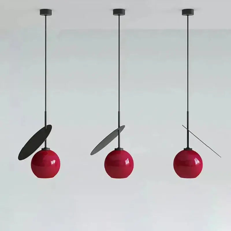 Three decorbites cherry glass pendant lights with glossy red spherical glass shades and matte black accents for home decor