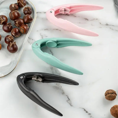 Three colorful decorbites chestnut cracker tools in pink mint green and black on marble next to a chestnut tray