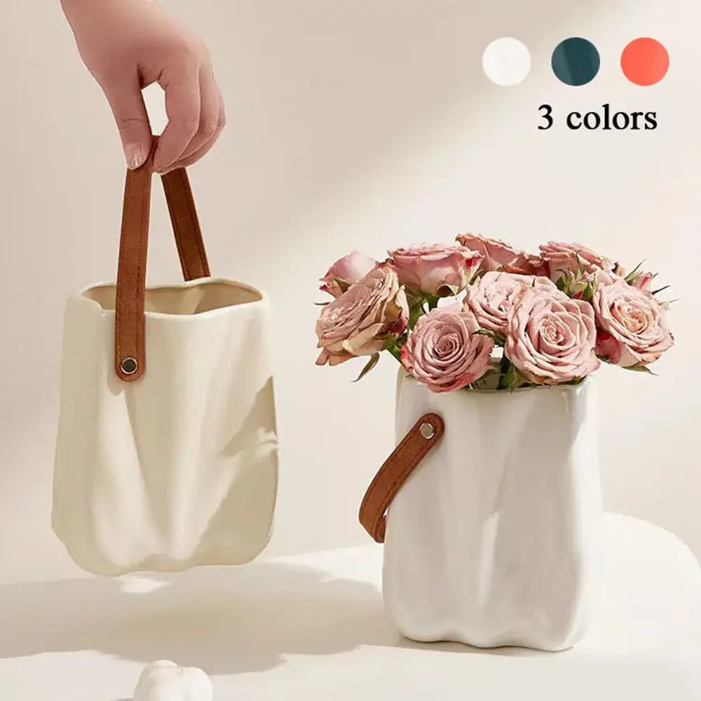 Cream-colored chic ceramic vase with textured wavy surface and brown leather handle for home decoration