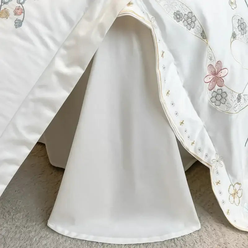 White satin bed skirt with soft pink gray and gold floral embroidery along scalloped edge in decorbites chic flowers bedding set