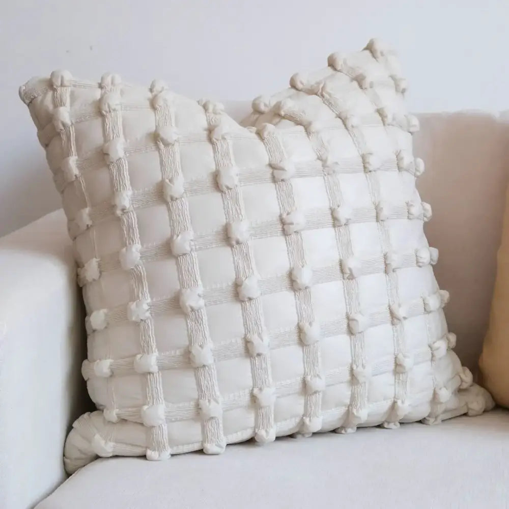Cream-colored decorbites chic pillow with textured grid pattern of raised pom-poms in chic pillow cover set