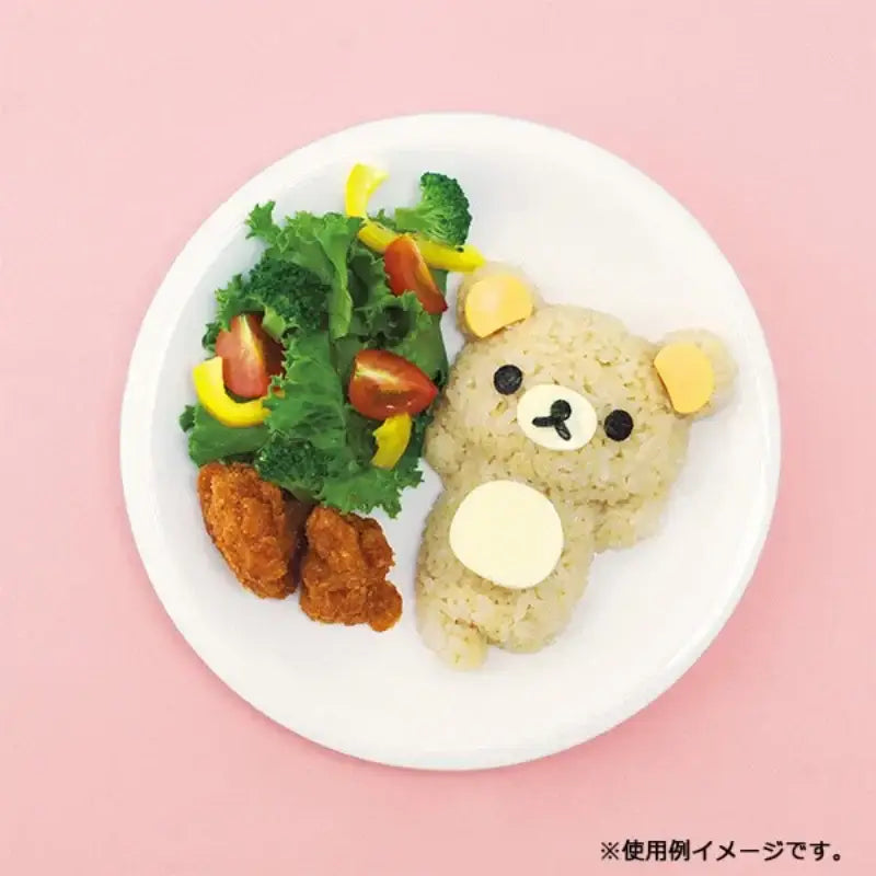 A cute beige rice ball shaped like rilakkuma with yellow ears made using decorbites chicken bear mold set