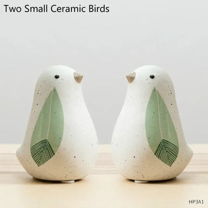 Two small speckled white ceramic bird figurines with green leaf wings and beige beaks for home decor by decorbites