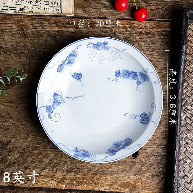 A set of two white porcelain vegetable plates with delicate blue floral patterns and matching blue rims by DecorBites