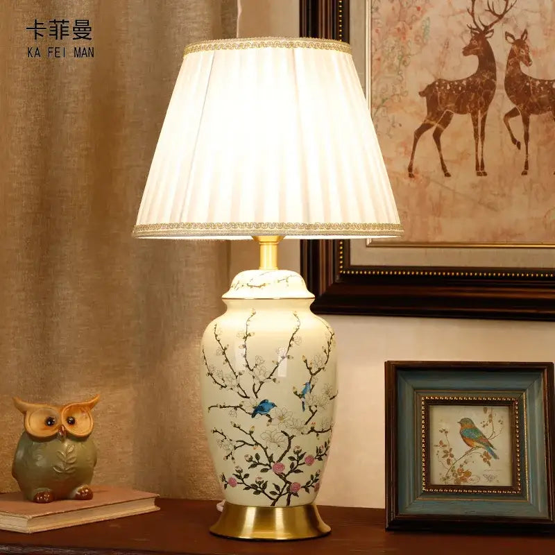 Cream-colored ceramic table lamp with hand-painted blue birds pink blossoms and gold trim for living room or bedroom