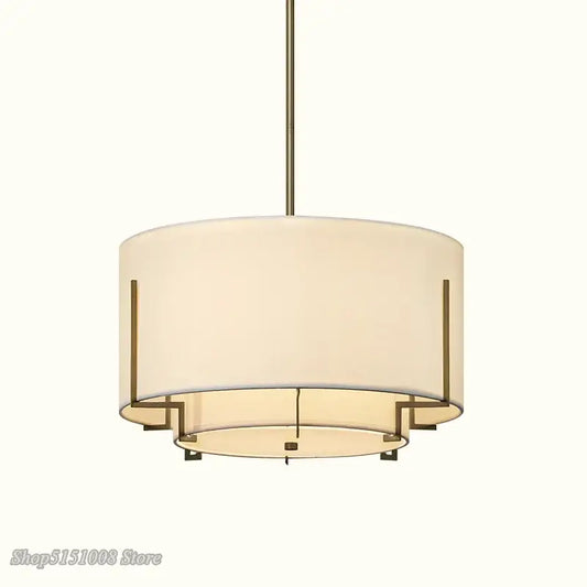 Modern minimalist living room pendant lamp with cream fabric shade and brass-toned metal drum frame by decorbites