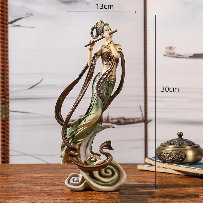 Detailed resin chinese goddess fairy figurine in green and gold robe playing flute on swirling clouds home decor piece