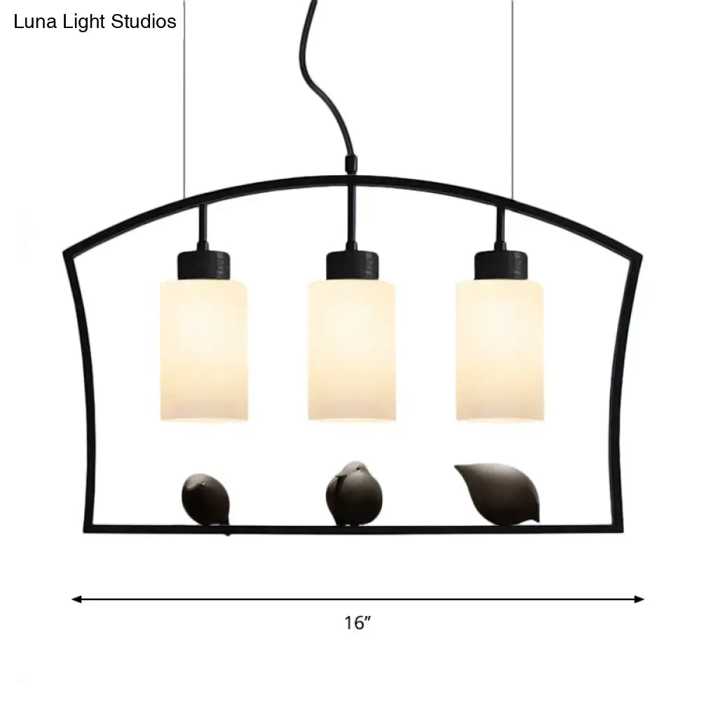 Black metal cylinder island light fixture with three frosted white glass shades and decorative bird figurines ceiling lamp