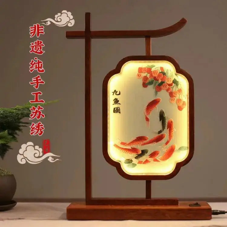A warm-lit wooden decoration screen with cream fabric embroidered desk lamp featuring koi fish and orange blossoms