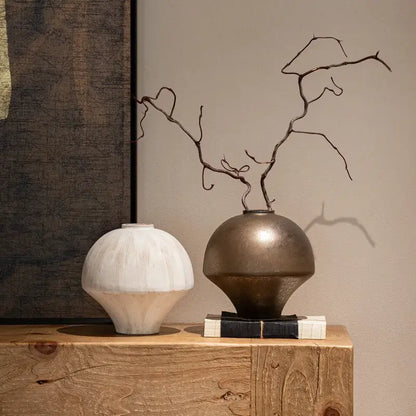 Bronze metallic retro porcelain vase with rounded body and narrow neck holding dark twisted branches for home decoration