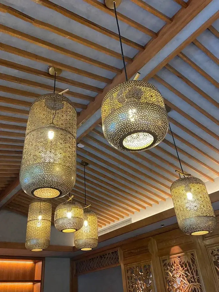 Golden intricately perforated metal zen art birdcage pendant light with warm glowing lights for restaurant tea room