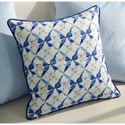 Square cream fabric cushion with navy blue bows and pink florals framed by navy border decorbites chinoiserie blue wavy fan