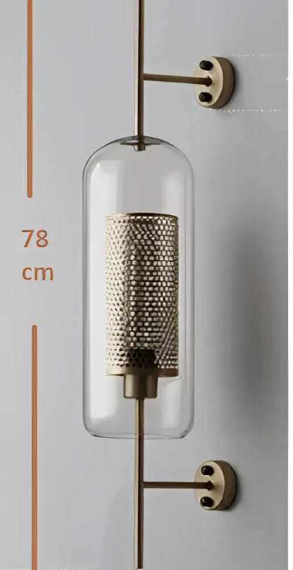 Decorbites™ chiswick glass wall light is a modern brass-finished glass wall light with intricate mesh interior and clear cylinder housing