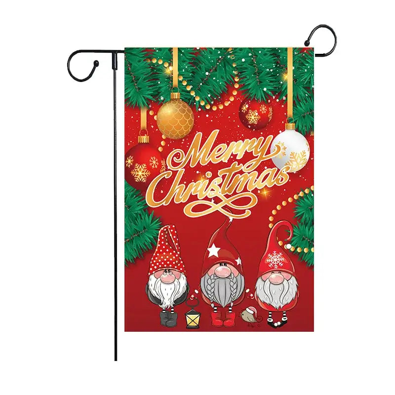 Red christmas garden flag by decorbites featuring three cartoon gnomes, festive ornaments, pine branches, and gold lettering