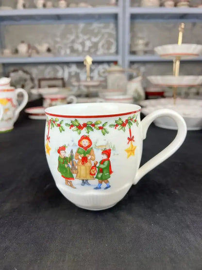 White ceramic mug from decorbites christmas dinnerware set featuring festive children illustrations and holly berry accents