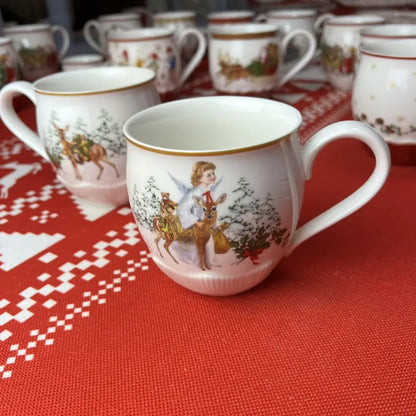 White ceramic christmas mug with gold rim featuring painted angel and deer scene from decorbites christmas dinnerware set