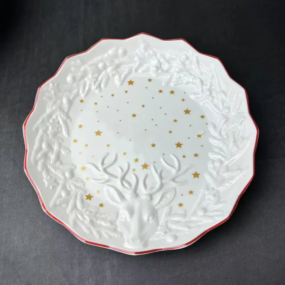 White ceramic plate with red scalloped edge embossed deer head and laurel wreath from DecorBites Christmas dinnerware set