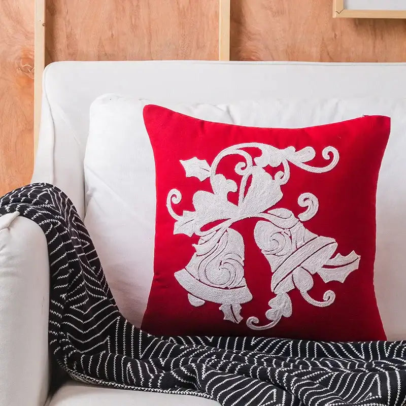 Red cushion cover with white embroidered bells and holly design from decorbites christmas embroidered collection