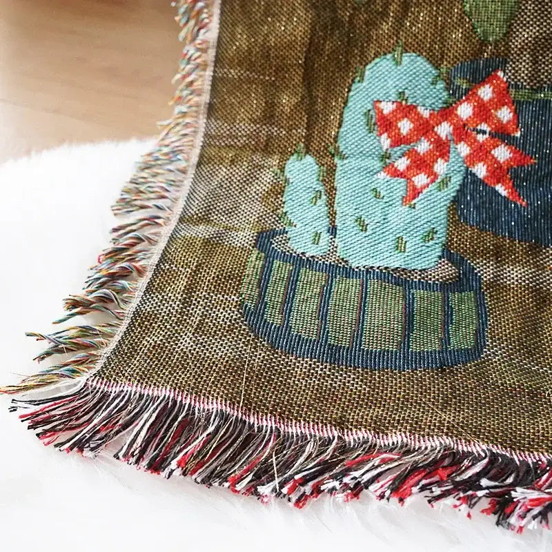 A cozy olive-green woven decorbites christmas holiday sofa blanket with turquoise cactus and multicolored fringe