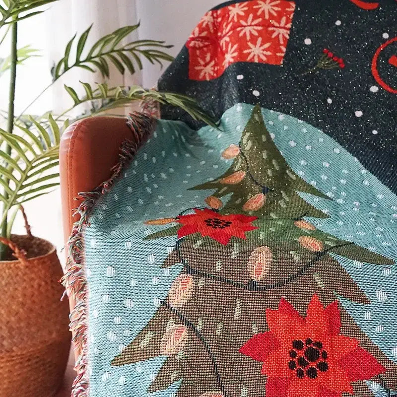 Cozy teal DecorBites Christmas holiday sofa blanket with festive tree, red poinsettias, snowflakes, and frayed edges
